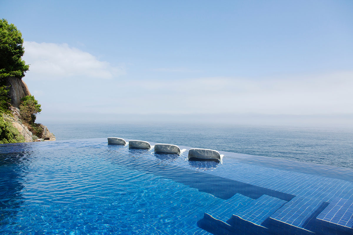 Lounge chairs in infinity pool overlooking ocean